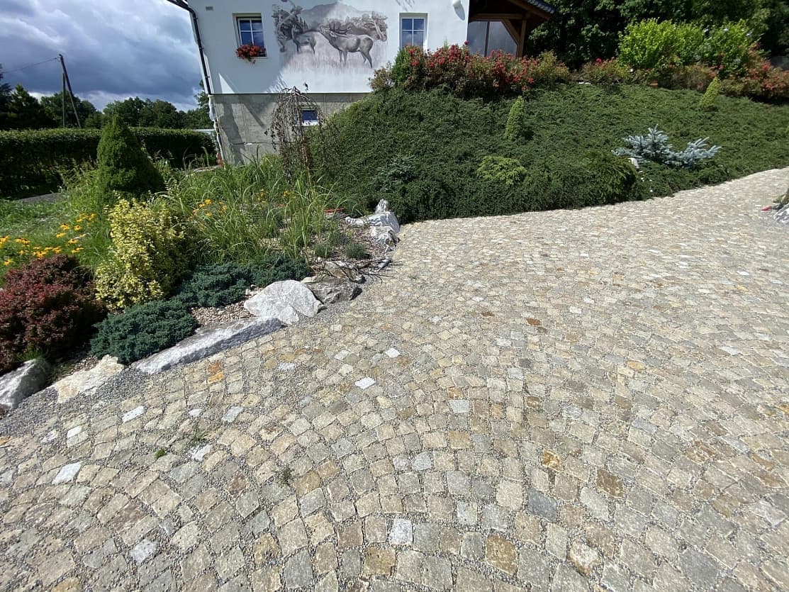 Příjezdová cesta ze žlutých žulových kostek ladící s okolní zahradou u venkovského ubytování ve Staré Červené Vodě