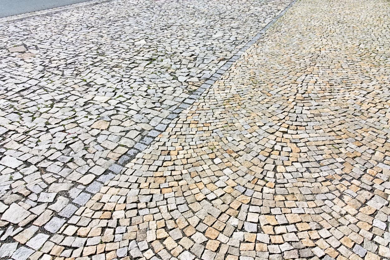 Detail žulových kostek a odštěpků v šedožlutém odstínu, tvořících esteticky harmonický a odolný povrch veřejného prostranství.