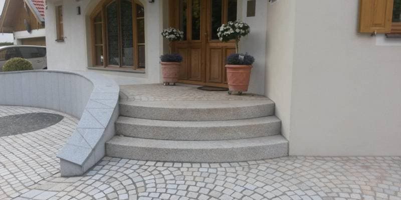 Elegantní vstupní schodiště z žuly s obloukovými stupni, žulovým obkladem zídky a dlažbou z formátovaných žulových kostek.