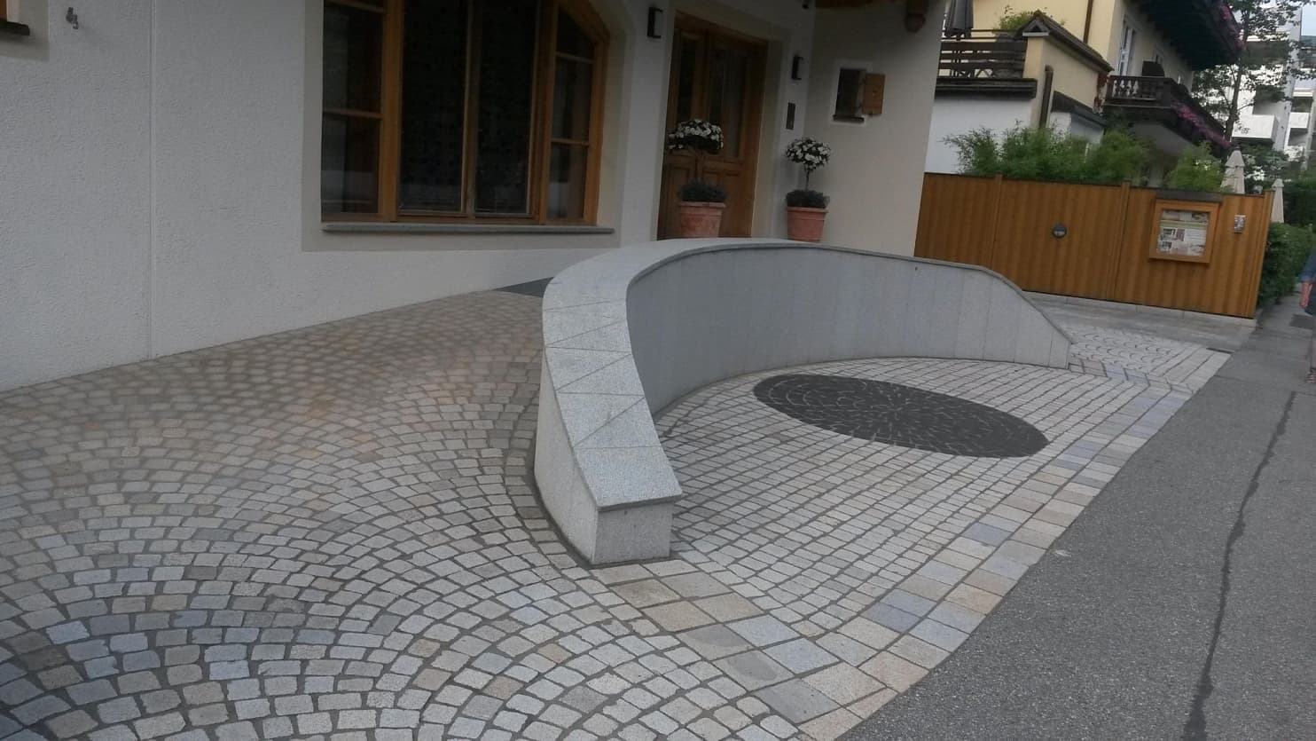 Vstupní prostor s obloukovou žulovou dlažbou, elegantní zídkou s kamenným obkladem a dekorativními prvky z přírodního kamene.