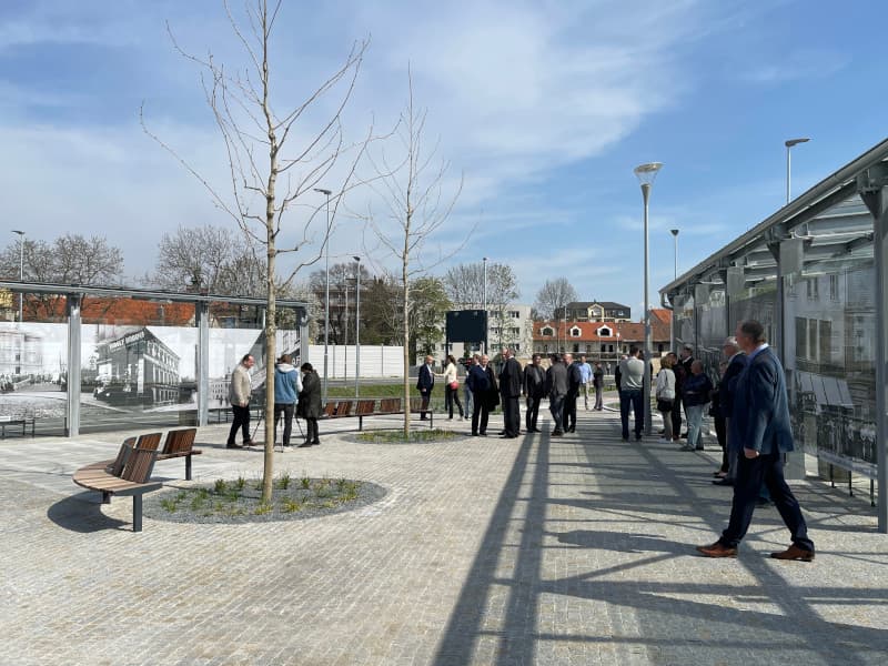 Autobusový terminál v Kralupech nad Vltavou s žulovou dlažbou, lavičkami a prosklenou čekárnou s historickými fotografiemi.