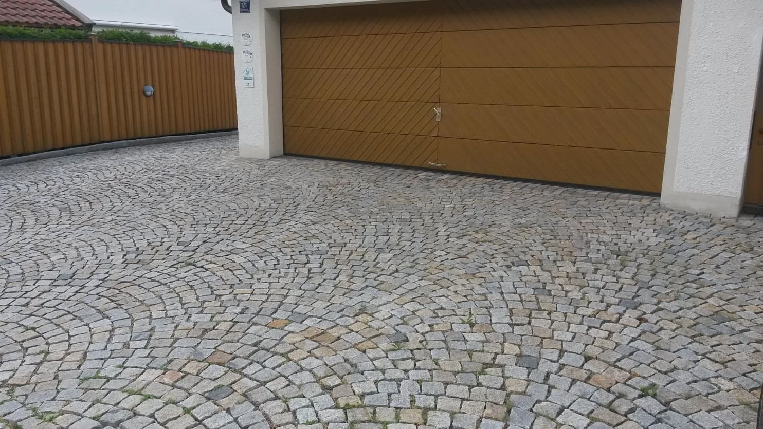 jezd do garáže s dlažbou z žulových kostek v obloukovém vzoru, vytvářející elegantní a odolný povrch.