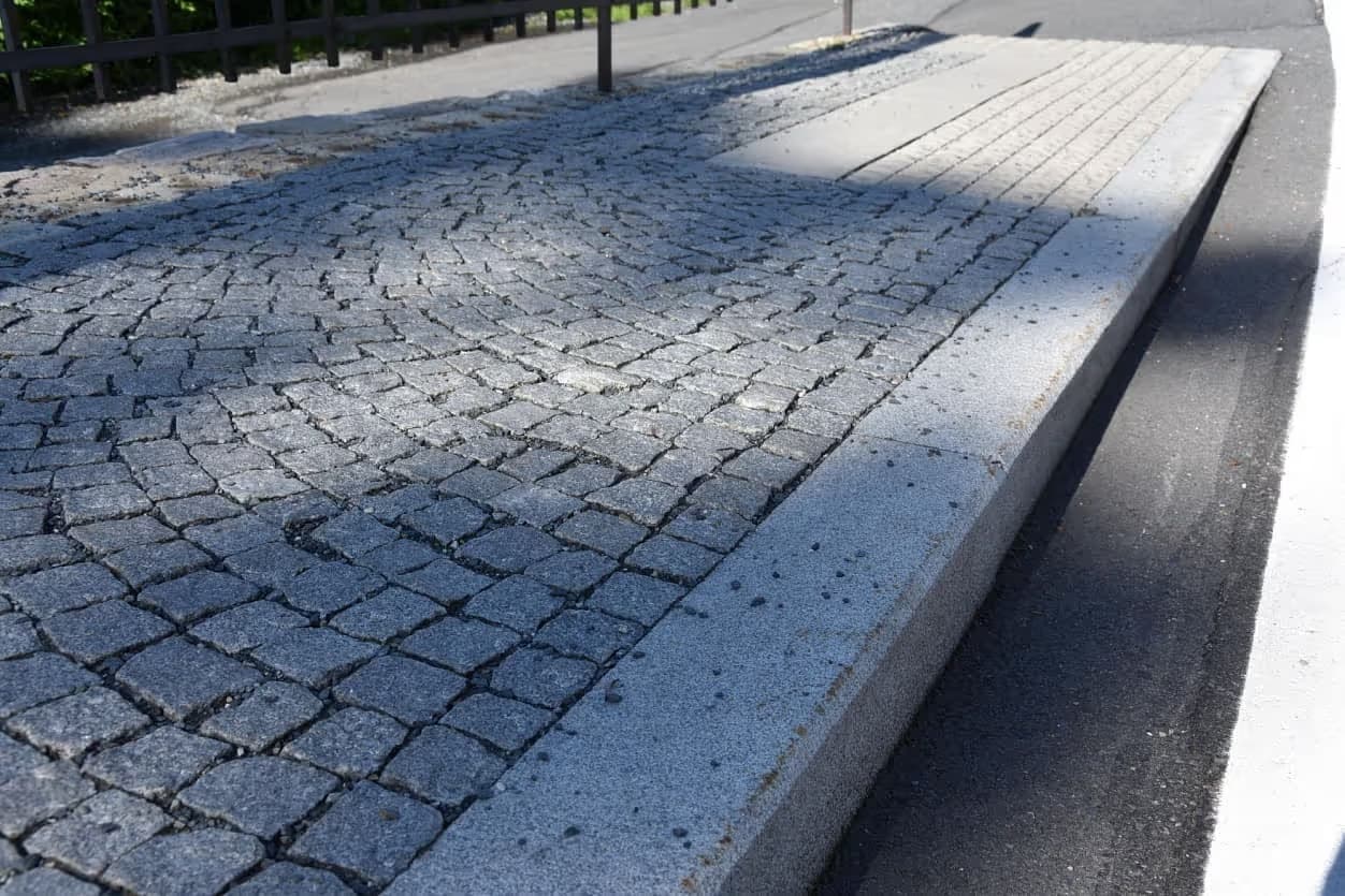 Autobusového nástupiště s obloukovou žulovou dlažbou a masivním žulovým obrubníkem v Priessnitzových léčebných lázních.