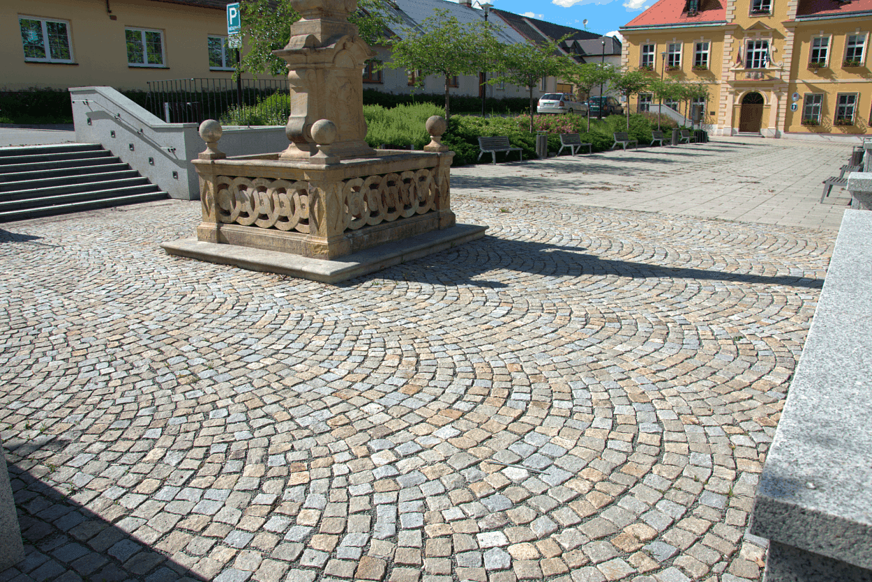 Žulová dlažba šedožlutá s fontánou.