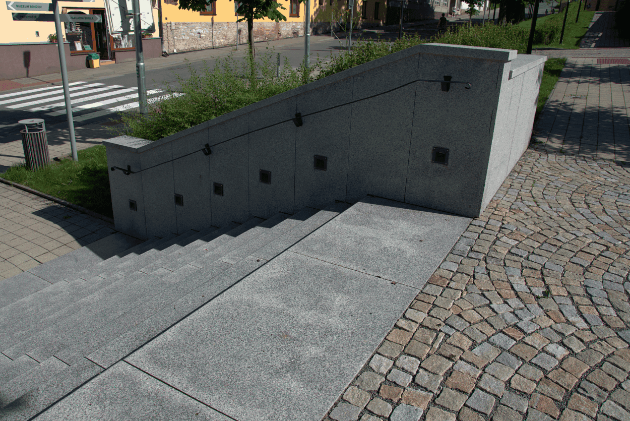 Žulové dlažební kostky v šedožluté barevnosti. Cesta po schodech ze žuly směrem dolů. 